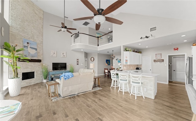 living room with a fireplace, high vaulted ceiling, and light hardwood / wood-style floors