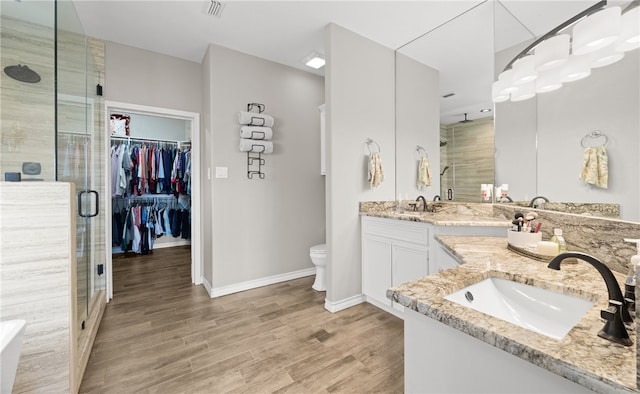 bathroom featuring toilet, vanity, a shower with shower door, and hardwood / wood-style flooring