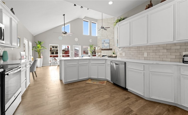 kitchen featuring white cabinets, stainless steel appliances, high vaulted ceiling, and light hardwood / wood-style floors