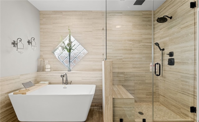 bathroom with shower with separate bathtub and tile walls