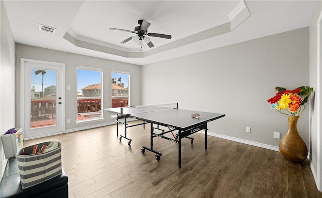 game room with a tray ceiling, ceiling fan, and dark wood-type flooring