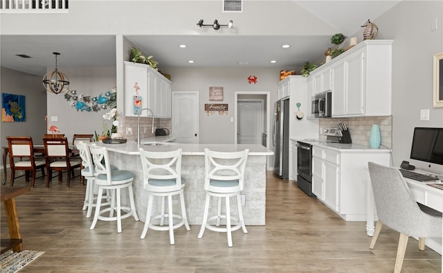 kitchen with a breakfast bar area, light hardwood / wood-style flooring, appliances with stainless steel finishes, and tasteful backsplash