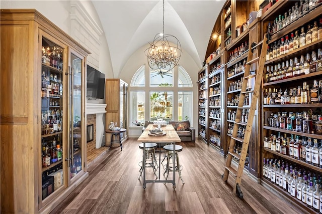 interior space with a notable chandelier, wood finished floors, a fireplace, and vaulted ceiling