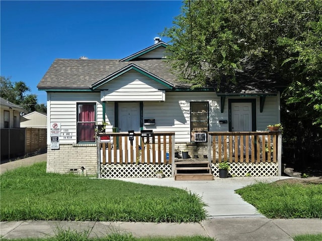 bungalow-style house featuring a shingled roof, crawl space, covered porch, and fence