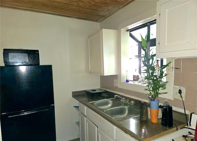 kitchen with decorative backsplash, freestanding refrigerator, wood ceiling, white cabinets, and a sink