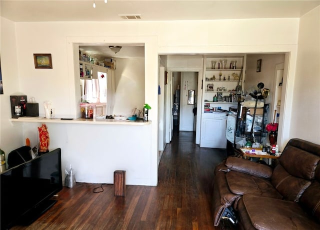 living area with washer / clothes dryer, visible vents, and wood finished floors