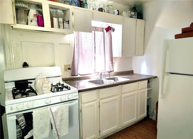 kitchen with open shelves, white appliances, dark countertops, and a sink