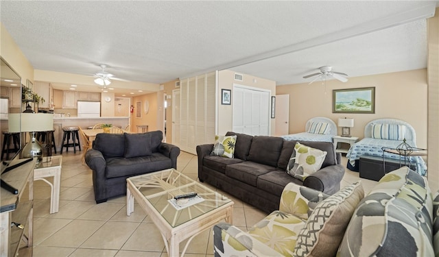 living room with a textured ceiling, ceiling fan, and light tile patterned floors