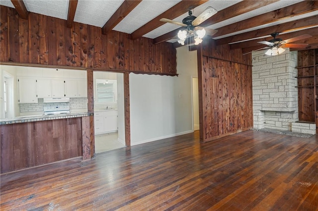 unfurnished living room featuring dark wood-type flooring, wood walls, lofted ceiling with beams, and ceiling fan