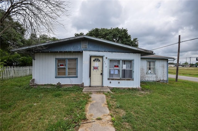 bungalow-style home with fence and a front lawn