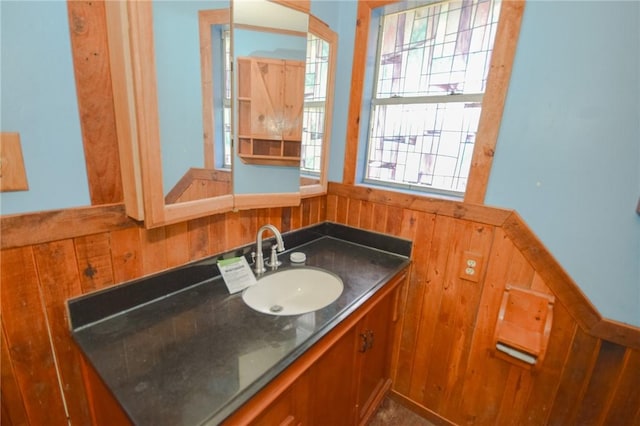bathroom featuring vanity, wooden walls, and wainscoting