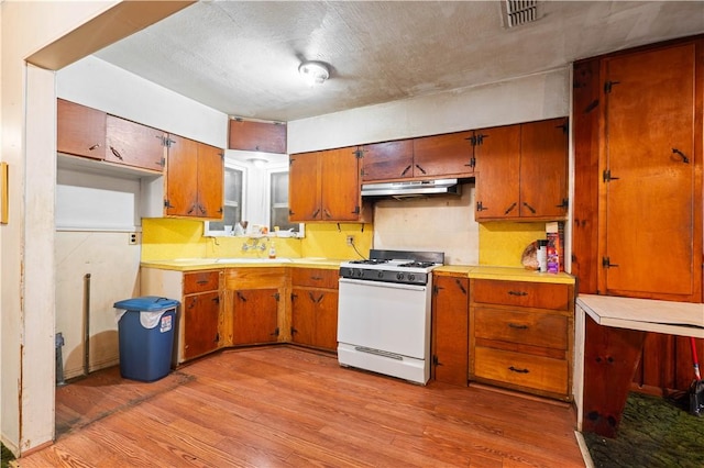 kitchen with visible vents, gas range gas stove, light wood-style flooring, and under cabinet range hood