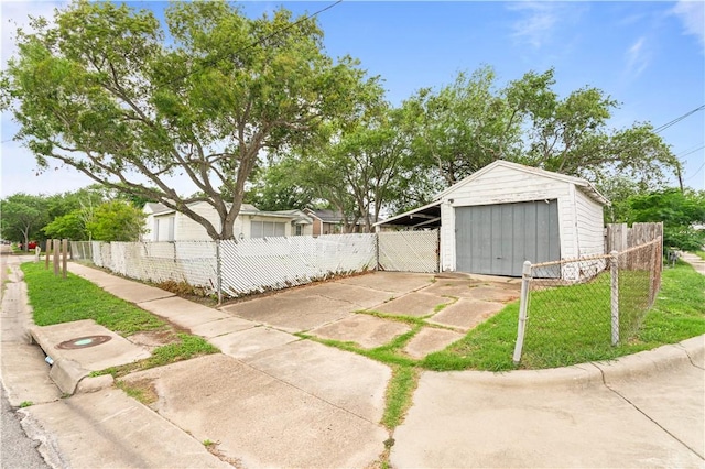 exterior space with fence, a detached garage, an outdoor structure, a yard, and driveway