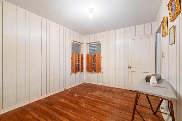 empty room featuring baseboards, wood walls, and hardwood / wood-style floors