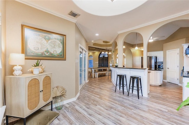 kitchen featuring visible vents, arched walkways, dark countertops, a kitchen bar, and white cabinetry