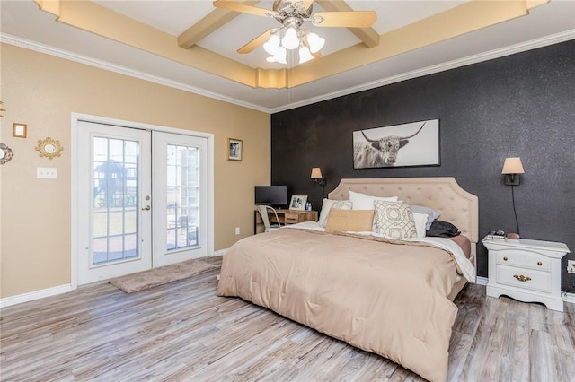 bedroom featuring an accent wall, wood finished floors, and a raised ceiling