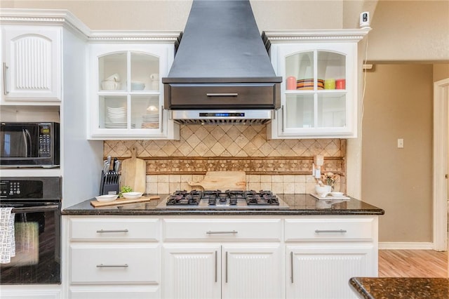 kitchen with premium range hood, backsplash, dark stone counters, black appliances, and glass insert cabinets