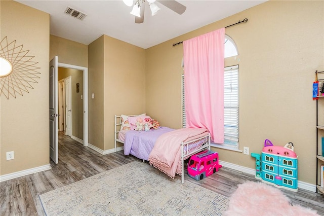 bedroom featuring a ceiling fan, baseboards, visible vents, and wood finished floors