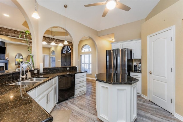 kitchen featuring freestanding refrigerator, black dishwasher, a sink, and light wood-style flooring