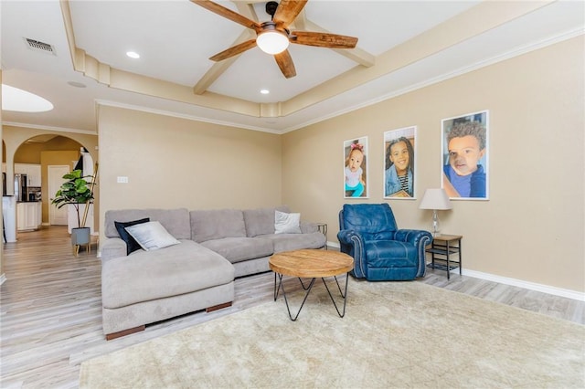 living area featuring arched walkways, wood finished floors, visible vents, and baseboards