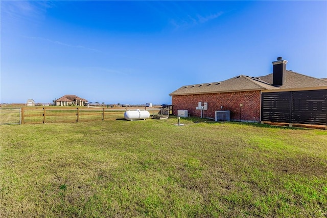 view of yard with central AC and fence