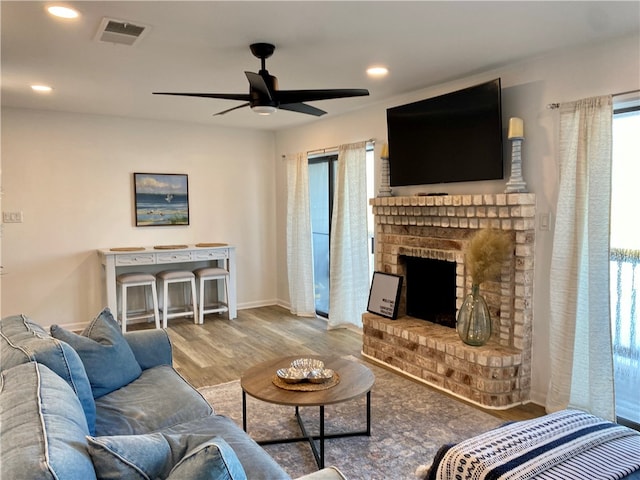 living room with wood-type flooring, ceiling fan, and a fireplace