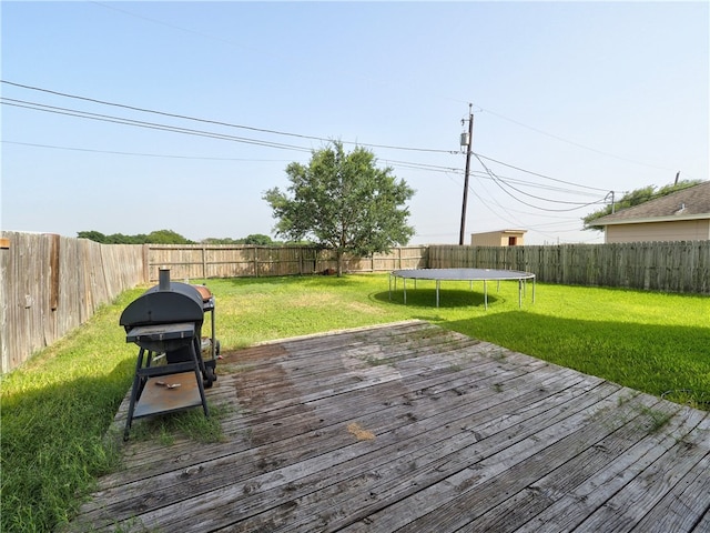 deck featuring a lawn, a trampoline, and area for grilling