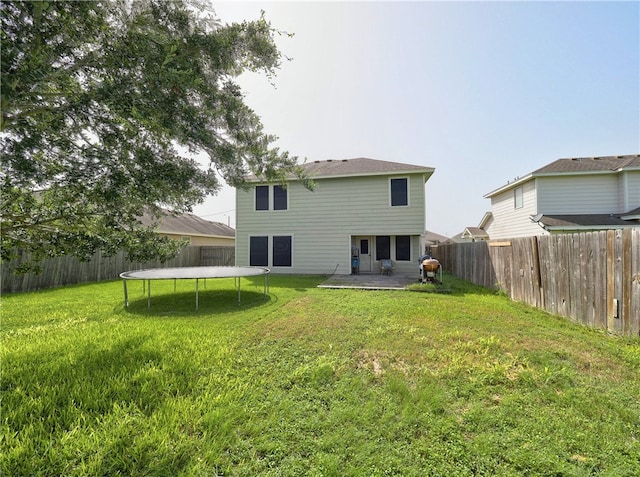 rear view of house featuring a patio, a yard, and a trampoline