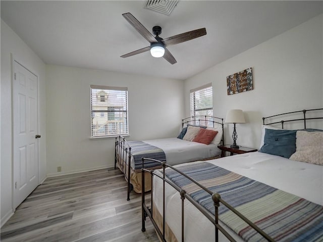 bedroom with light wood-type flooring, baseboards, and a ceiling fan