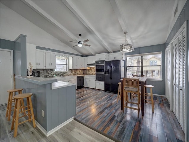 kitchen with black appliances, a peninsula, ceiling fan, and dark wood-style floors