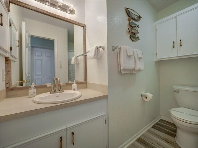 bathroom featuring toilet, wood finished floors, vanity, and baseboards