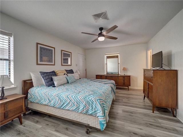 bedroom with light wood-type flooring, a ceiling fan, and baseboards
