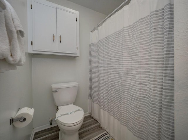 full bathroom with wood finished floors, baseboards, toilet, and a shower with shower curtain