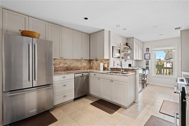 127 Sea Mist Dr, Aransas Pass, TX 78336 - kitchen with stainless steel appliances, a sink, decorative backsplash, light tile patterned floors, and light stone countertops