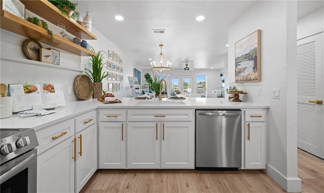 kitchen with appliances with stainless steel finishes, light wood-type flooring, sink, decorative light fixtures, and white cabinetry