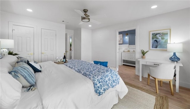 bedroom with hardwood / wood-style flooring, ceiling fan, ensuite bath, and multiple closets