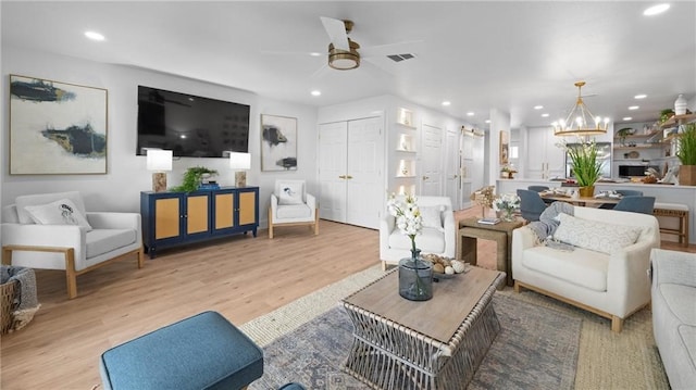 living room featuring light hardwood / wood-style flooring and ceiling fan with notable chandelier