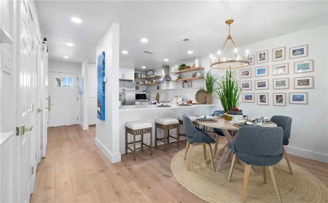 dining room with light hardwood / wood-style floors, sink, and a chandelier