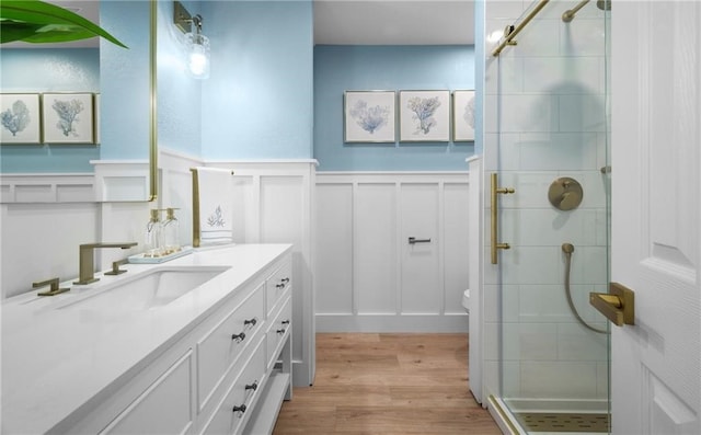 bathroom with hardwood / wood-style flooring, toilet, vanity, and walk in shower