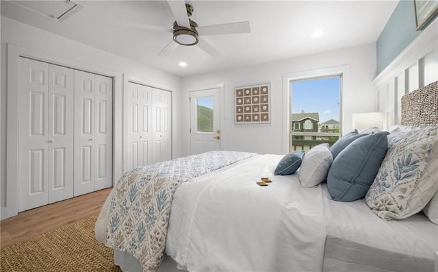 bedroom featuring hardwood / wood-style floors, ceiling fan, and multiple closets