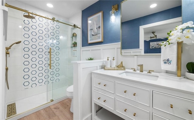 bathroom with hardwood / wood-style floors, vanity, toilet, and a shower with shower door