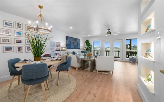 dining space with ceiling fan with notable chandelier, light wood-type flooring, and french doors