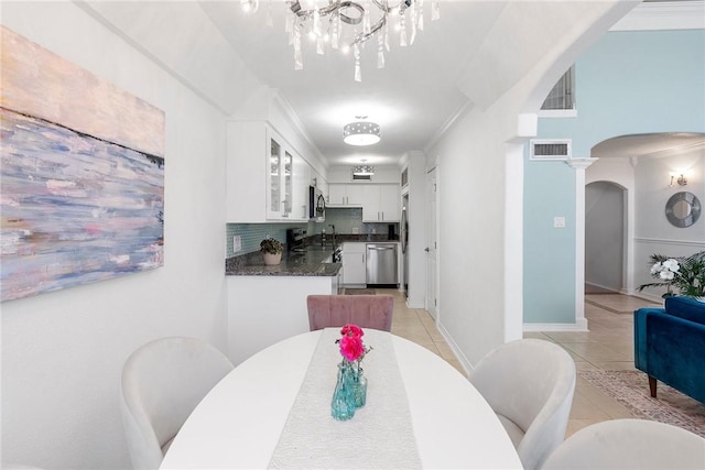 tiled dining room with a chandelier and ornamental molding