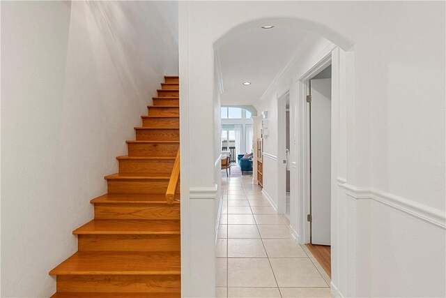 stairs with crown molding and tile patterned flooring