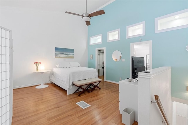 bedroom featuring a high ceiling, light hardwood / wood-style floors, and ceiling fan