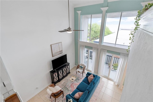 living room featuring ceiling fan, a healthy amount of sunlight, light tile patterned floors, and a towering ceiling