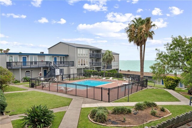 view of pool with a yard and a water view