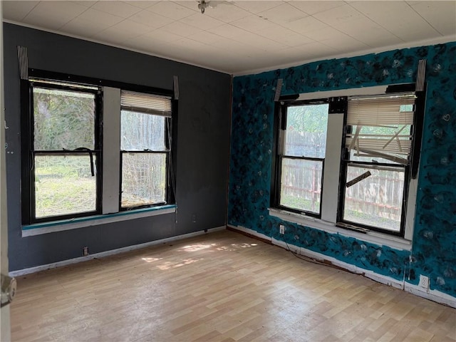 1210 King David Dr, Three Rivers, TX 78071 - empty room with healthy amount of natural light, wood finished floors, wallpapered walls, and ornamental molding