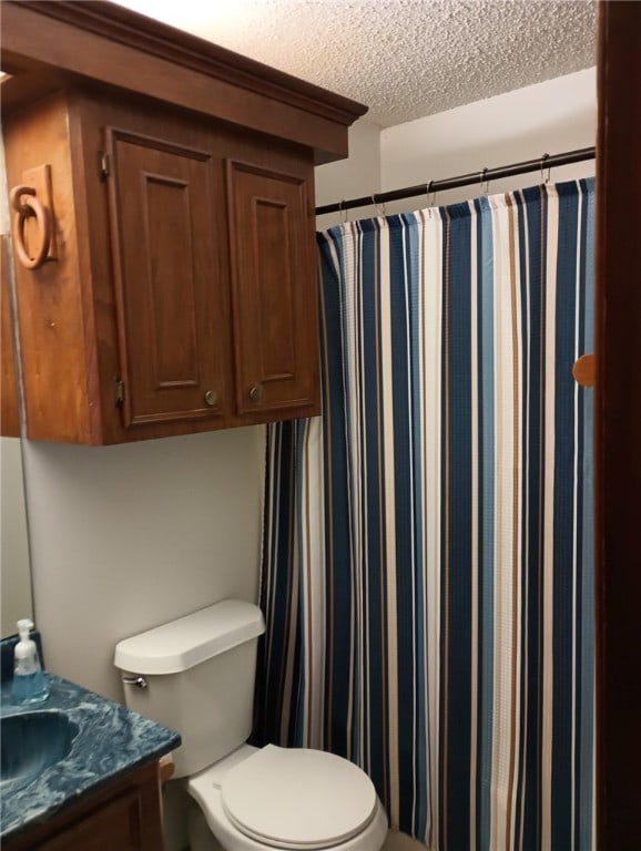 bathroom with vanity, toilet, and a textured ceiling