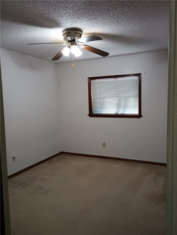 carpeted spare room featuring ceiling fan and a textured ceiling